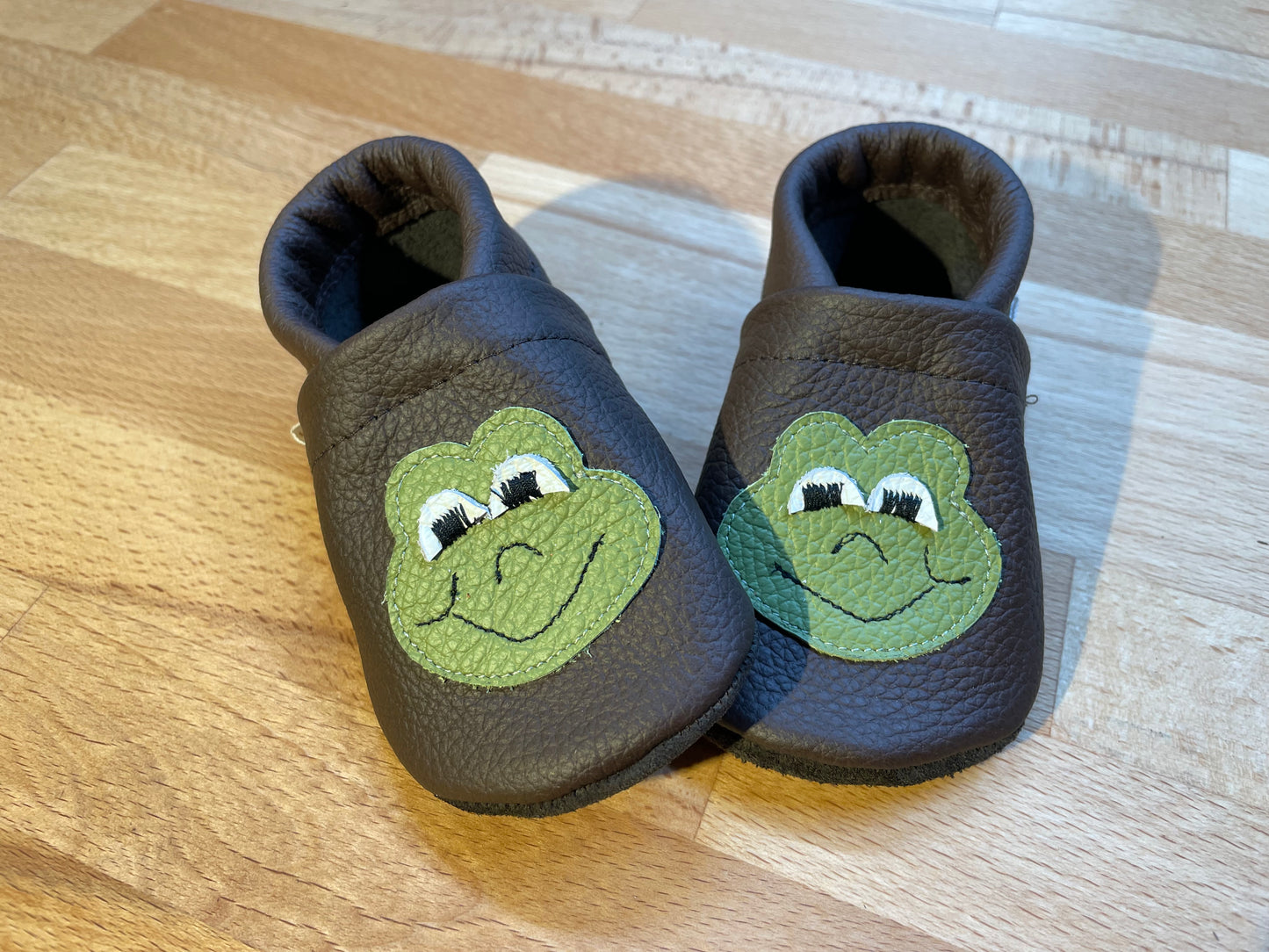 Dunkelbraune Lederpuschen mit einem Froschgesicht