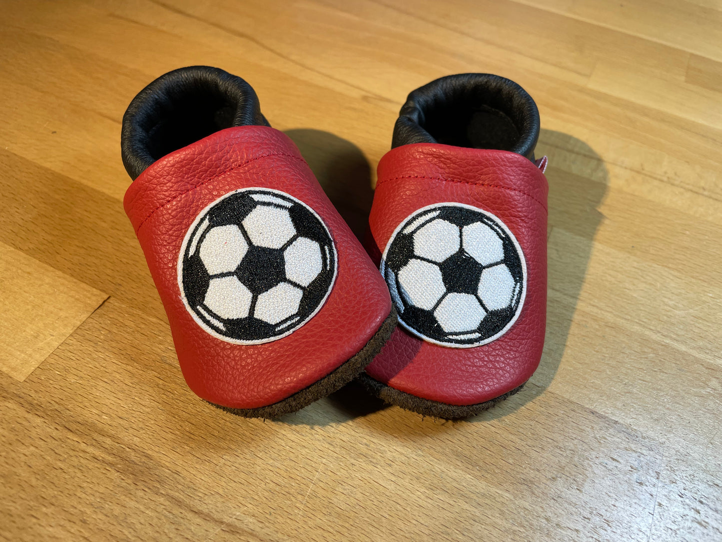 Rot-schwarze Lederpuschen mit Fußbällen