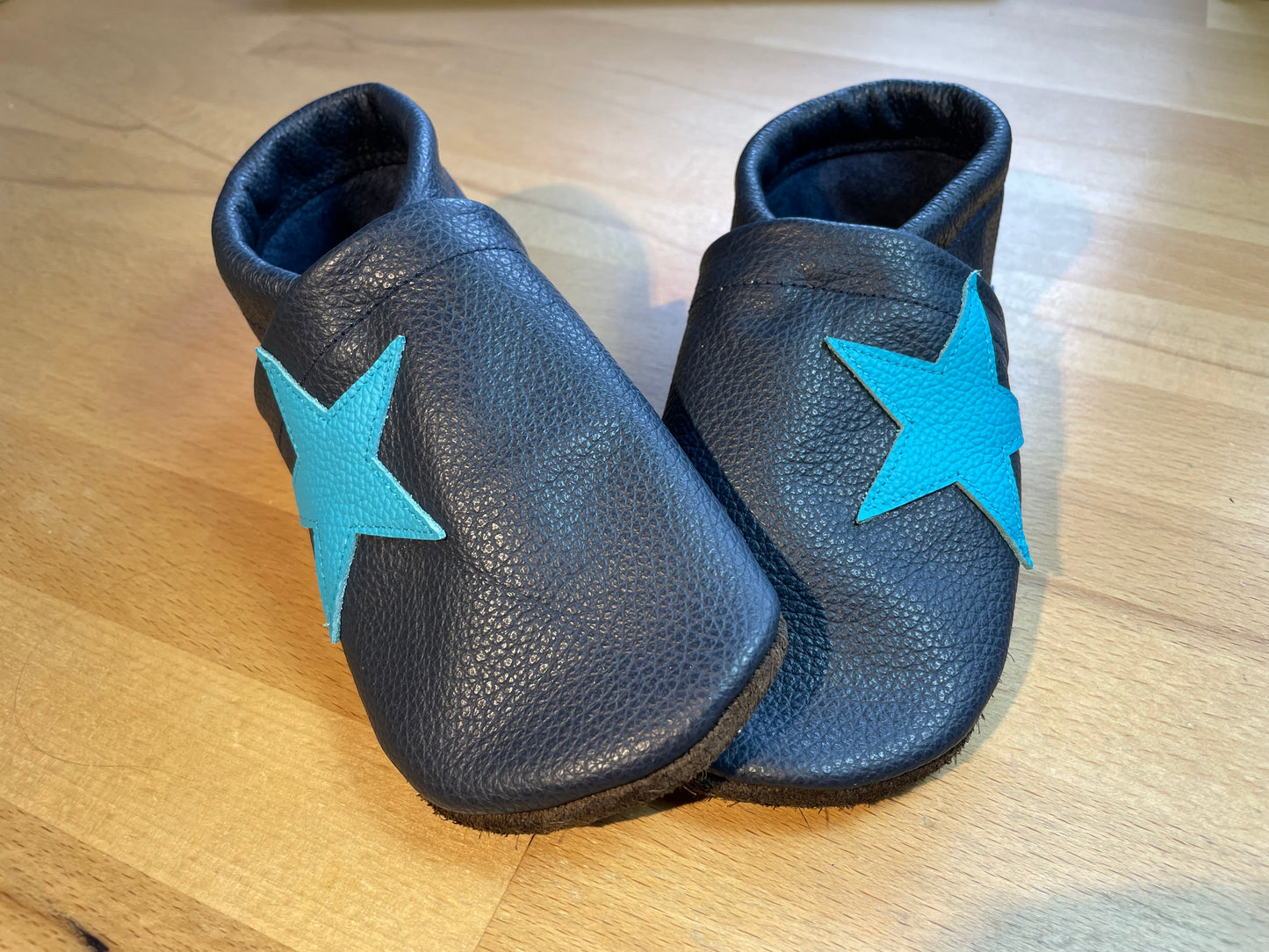 Dunkelblaue Lederpuschen mit einem türkisfarbene Stern