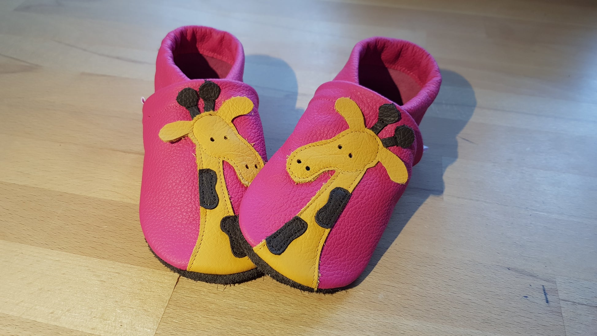 Pinkfarbene Lederpuschen mit einer Giraffe